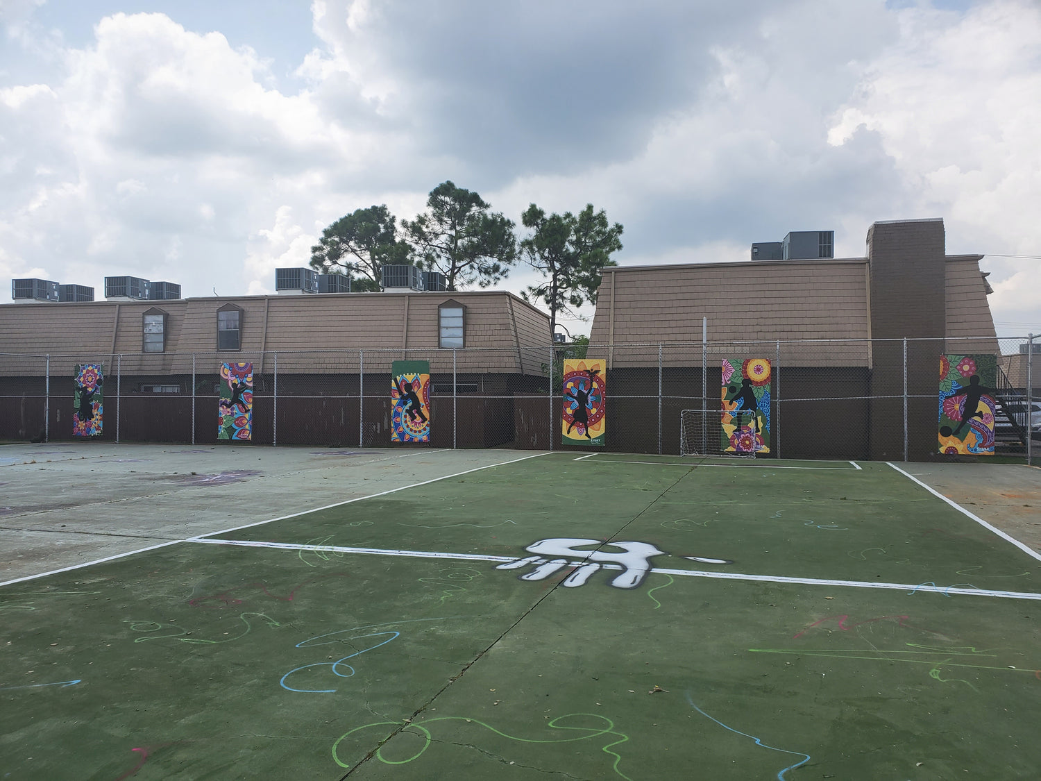 Mural for inner city kids in Gulfton, Houston, Texas. Mural is by Amy Malkan, a female artist and muralist. Mural has kids playing and a colorful mandala background.